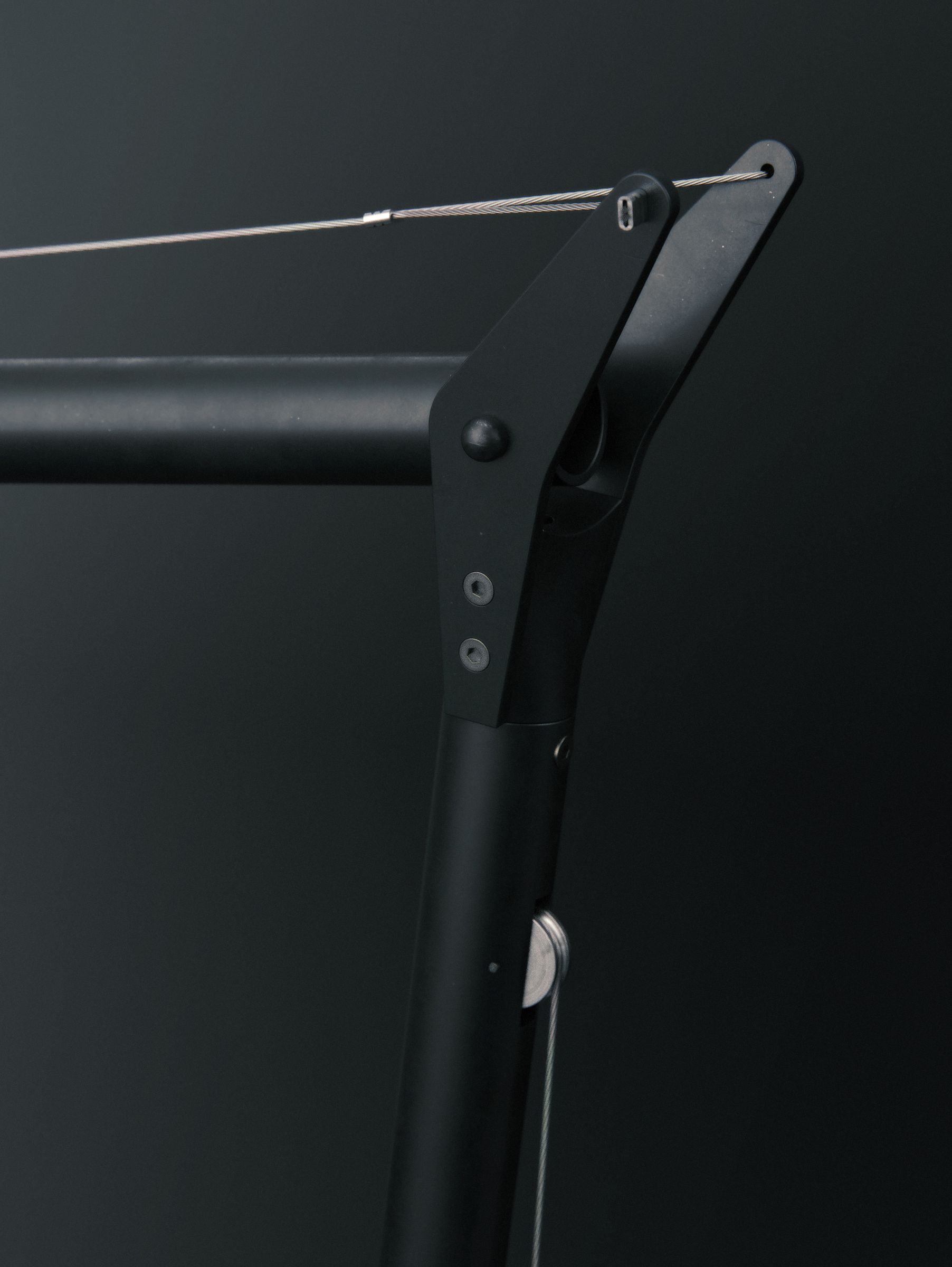 Close-up of an arm joint showing the tensioning cable and a sliding bracket mechanism running along the arm.