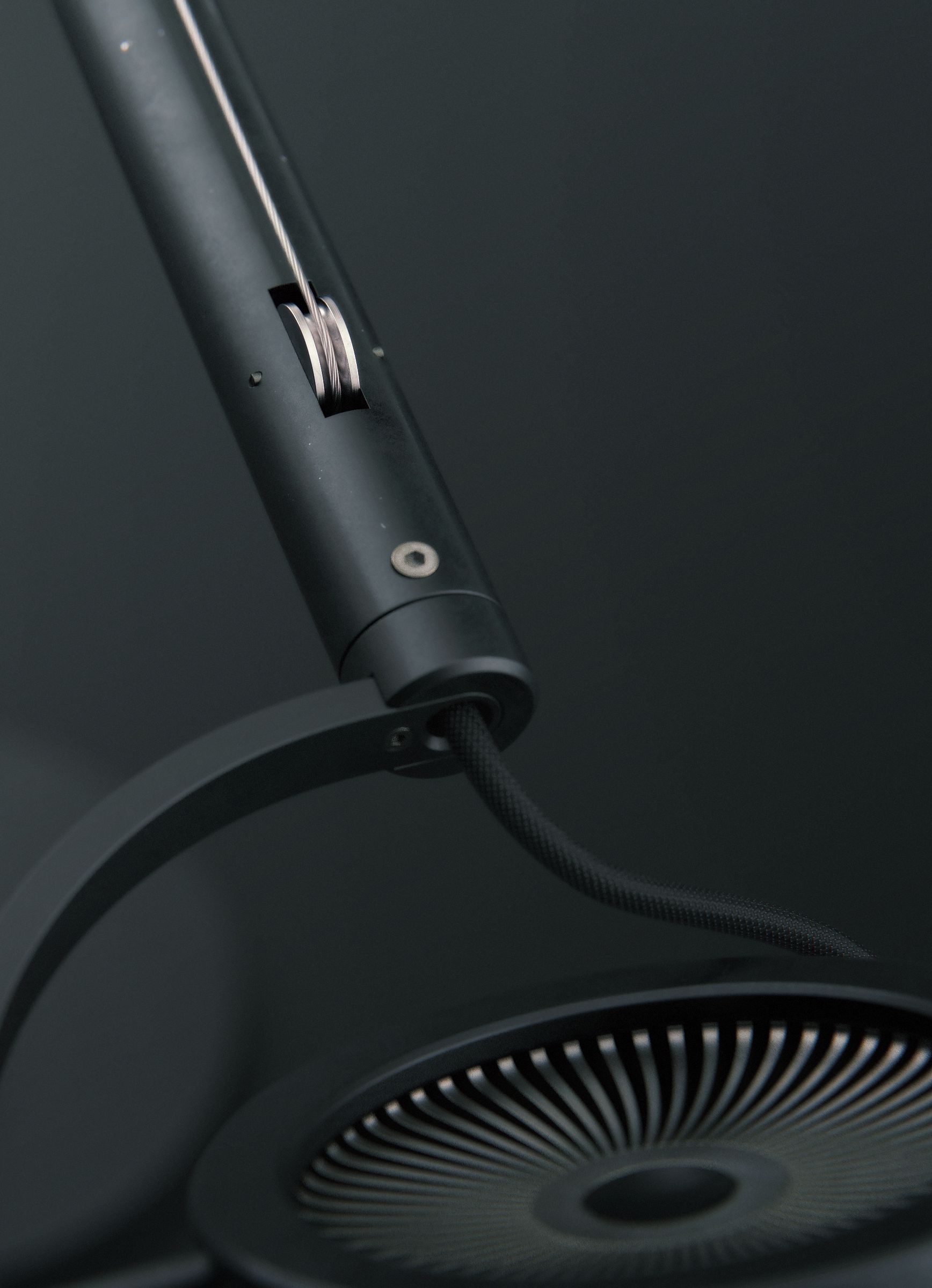 Close-up of the lower arm joint and finned lamp head, showing the tensioning cable that runs along the arm.