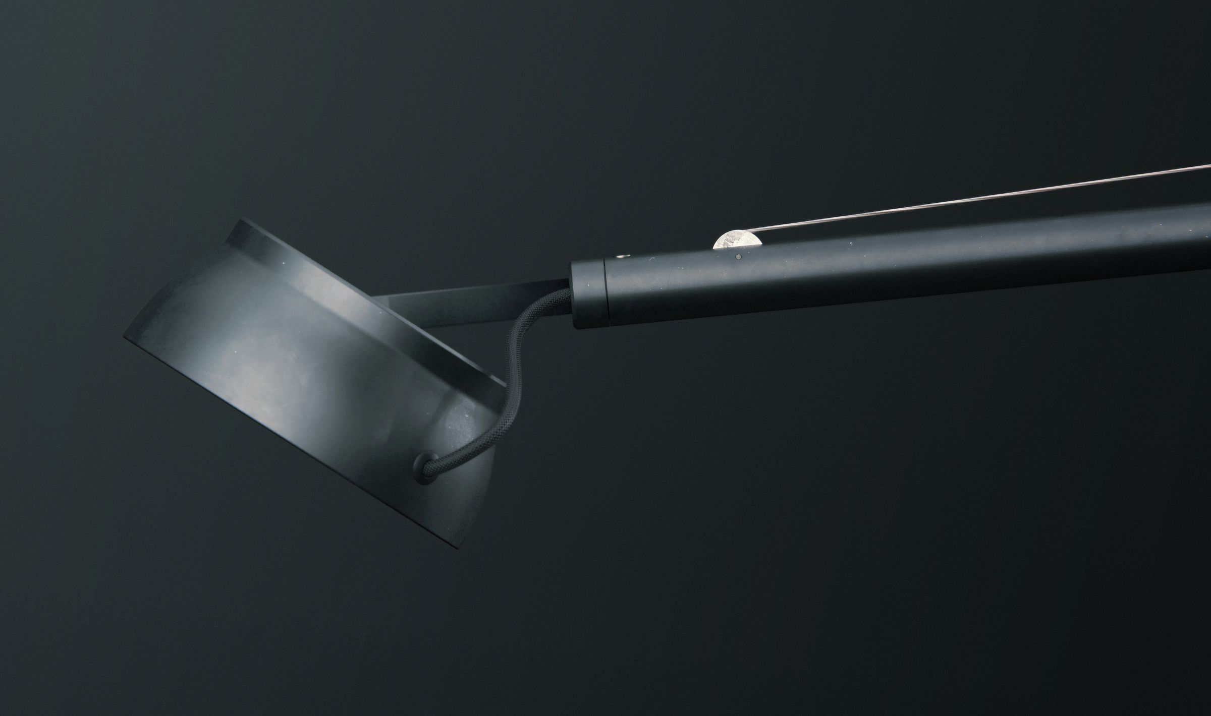 Side profile of the lamp head angled downward, showing its minimalist matte black finish.