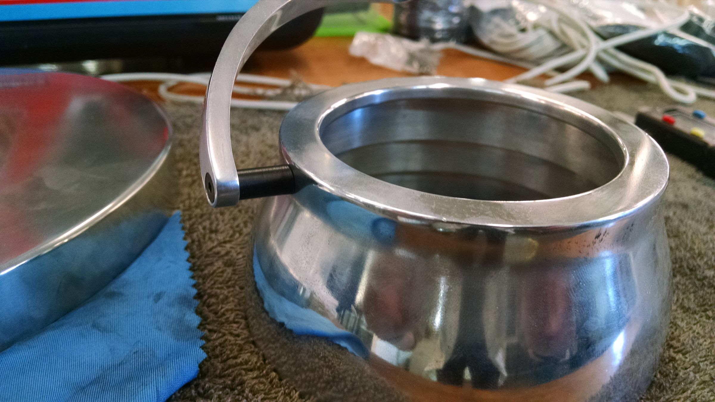Close-up of two curved metal lamp-head components sitting together, wrapped in blue protective tape.