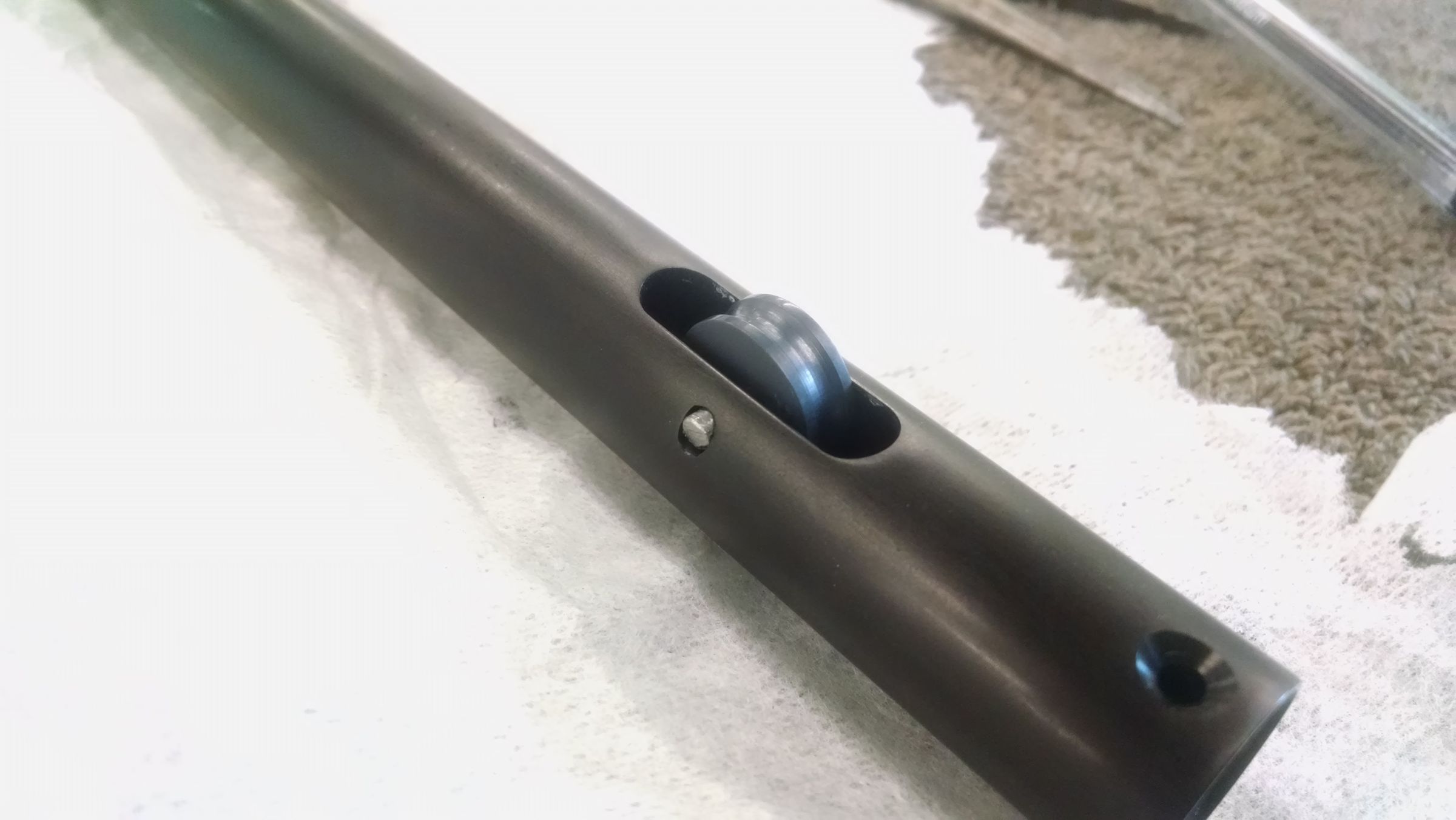 Close-up of a black cylindrical lamp arm component being sanded and finished by hand.