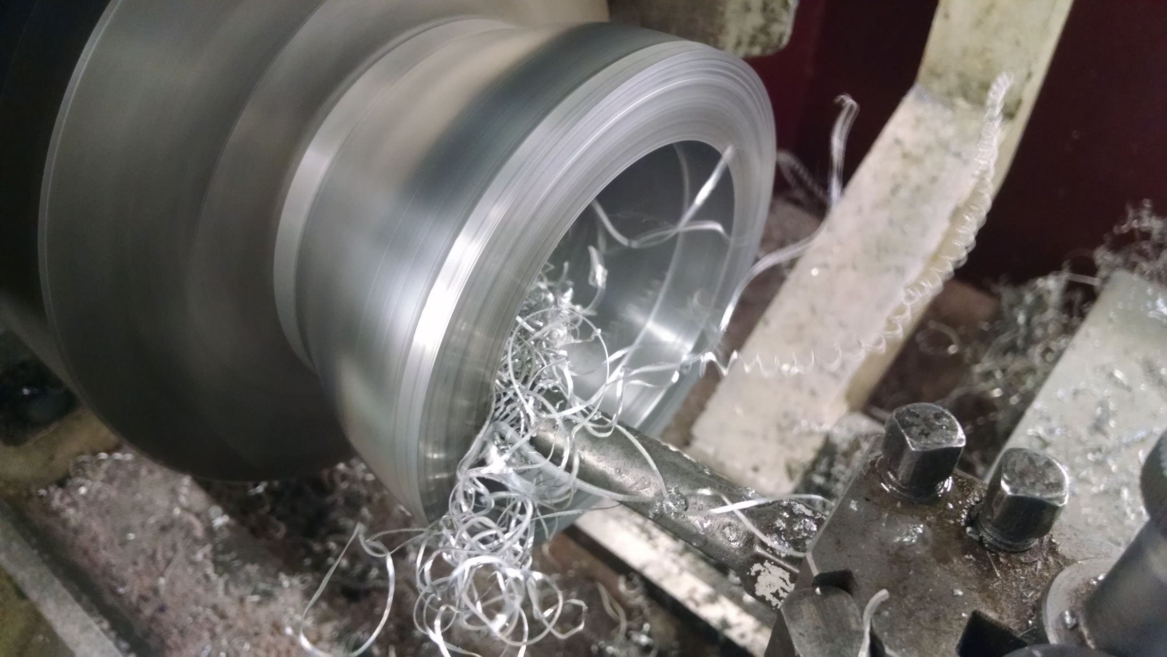 Close-up of a machined cylindrical metal part surrounded by curls of metal swarf.