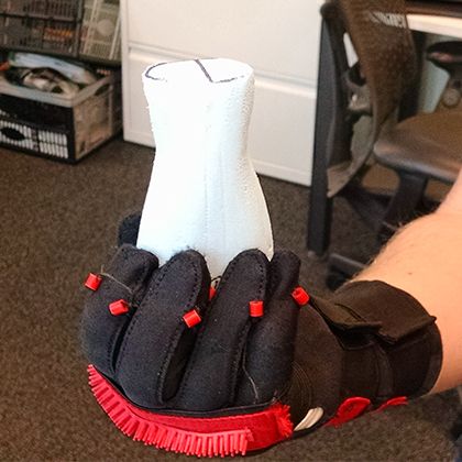 An early prototype: a padded black glove with a white wrist support and red foam pads, worn on a mannequin hand to explore hand stabilisation.