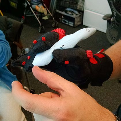 A hand testing the padded glove prototype with red foam elements, in a workshop setting.