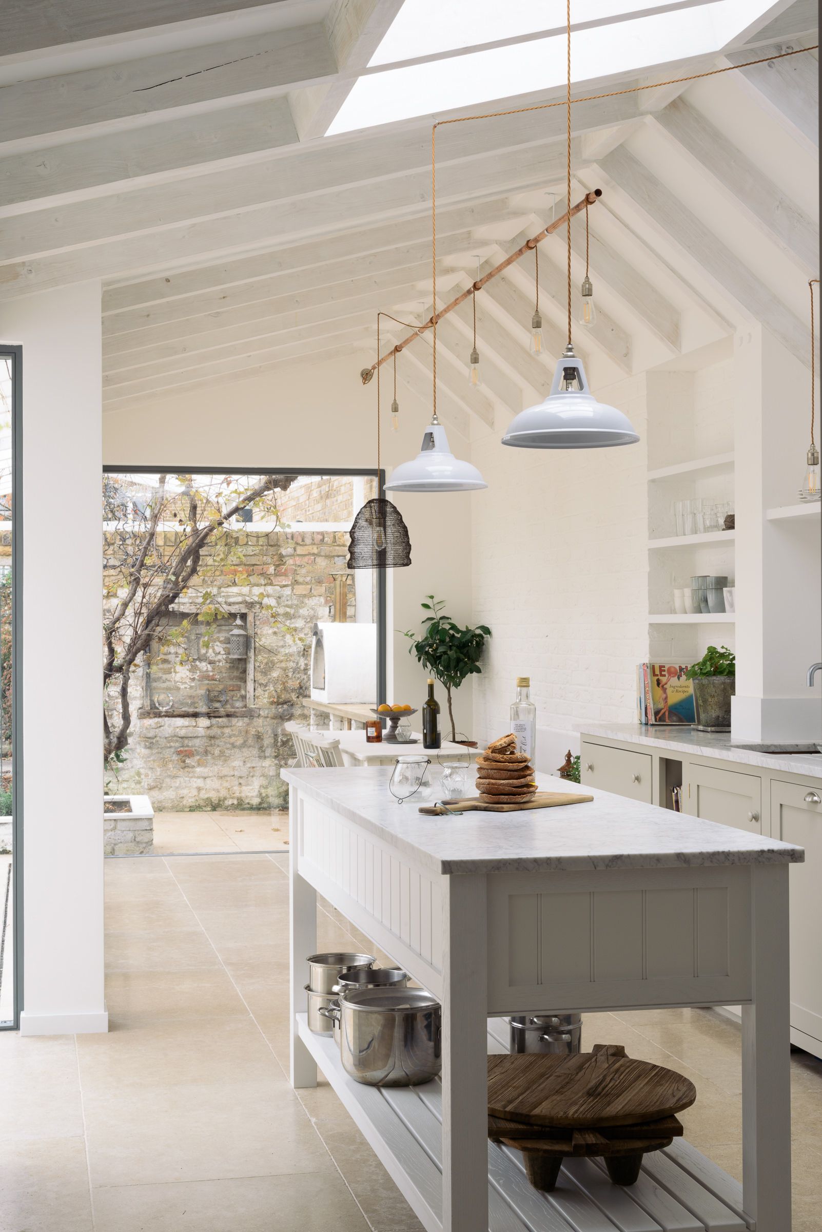 Wide view of the vaulted kitchen extension from the opposite end, showing the island, pendant lights, and glazed roof.